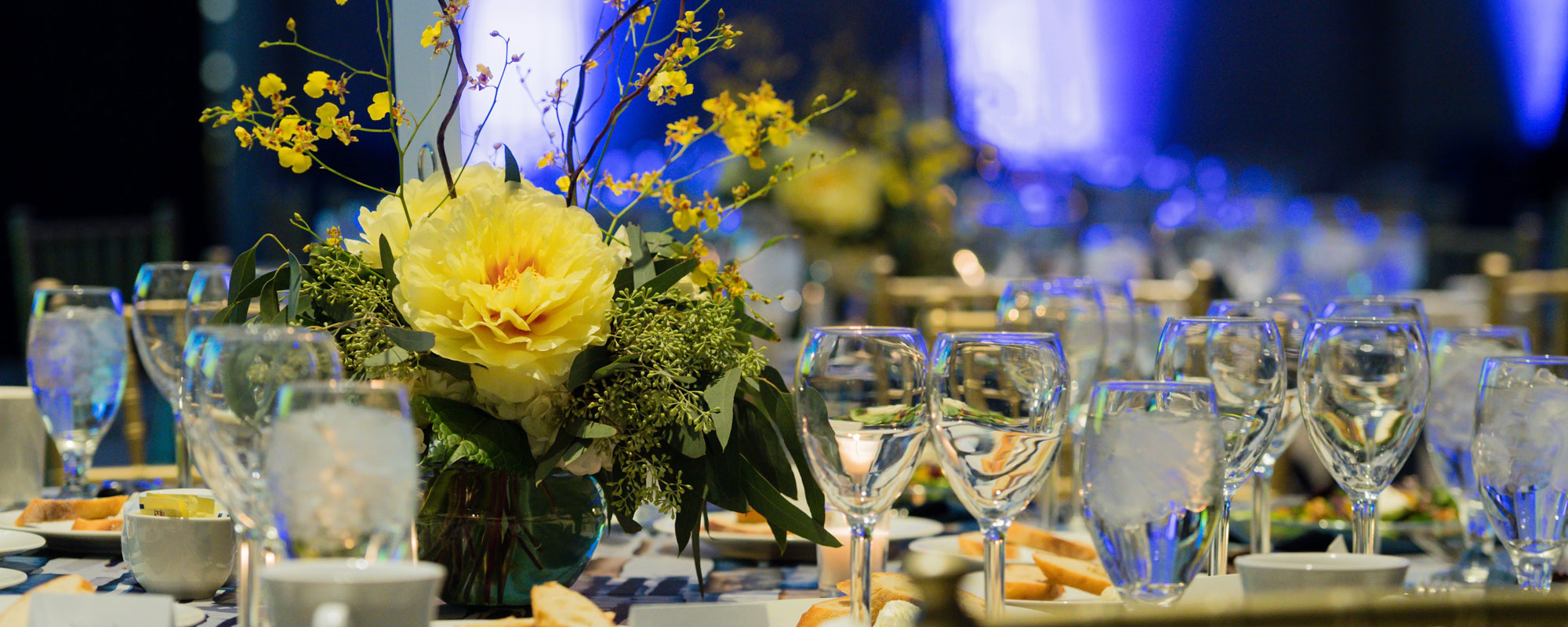 flowers, vases, glasses, and silverware on a tablecloth at a wedding